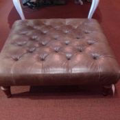 A buttoned brown leather stool on turned supports.