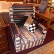 A contemporary armchair upholstered in brightly coloured striped fabric raised on castors.