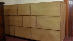 A contemporary light oak chest fitted arrangement of nine drawers and raised on block supports.