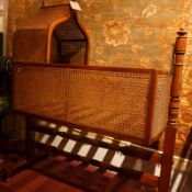 A French mahogany and bergere caned baby's crib raised on a turned and stretchered stand.