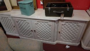 A large faux marble breakfront side cabinet fitted four trellis panel doors and raised on a plinth