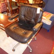 A pair of 1960's Gordon Russell office chairs upholstered in buttoned black leather and raised on