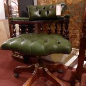 A mahogany desk chair upholstered in buttoned green leather with studded detail and raised on