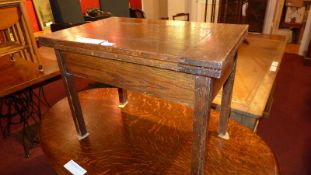 An oak foldover low table with storage compartment, raised on square section supports.
