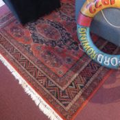 A Persian design rug the red fields with all over foliate decoration within a navy border.