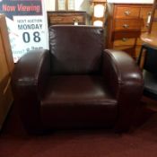 A Contemporary armchair upholstered in chocolate brown leather and raised on block supports.
