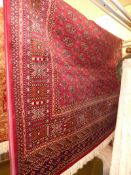 A Bokhara style carpet, the rouge field having repeating gul motifs in a triple border.
