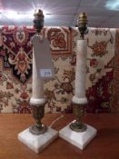 A pair of marble column form table lamps with gilt brass detail and raised on pedestal bases.