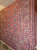 A Persian Bokhara rug the rouge ground having repeating gul motifs within a multi border.
