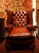 A Georgian style wing back armchair upholstered in buttoned leather with brass studded detail on