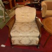 A pair of 1920's walnut bergere chairs upholstered in gold foliate damask on squat cabriole