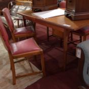 A McIntosh teak extending dining table with central butterfly leaf raised on tapering supports.