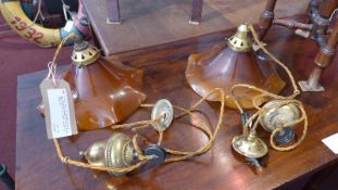 A pair of brass rise and fall ceiling lights with opaque brown glass shades of flared form together
