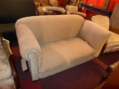 An Edwardian two seater drop end sofa upholstered in gold fabric raised on turned supports.