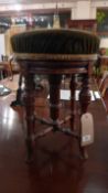 A Victorian rosewood piano stool with green velour upholstered seat raised on adjustable supports.