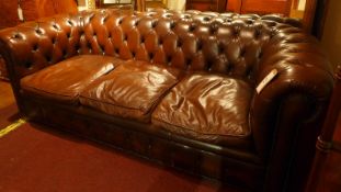 A 20th century Chesterfield three seater sofa upholstered in brown buttoned leather with brass