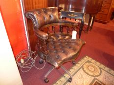 A 20th century captains chair upholstered in buttoned brown leather and raised on swivel supports.