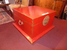 A Chinese red lacquered storage trunk / low table, of square form and with metal mounts.