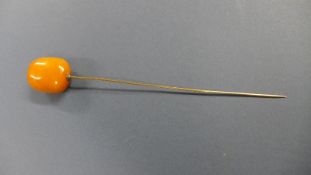 A Victorian gold metal and amber hat pin, the amber of strong butterscotch colour