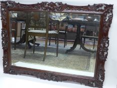 A Continental carved walnut wall mirror, the bevelled rectangular plate within ornate frame, 110cm x