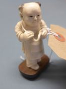 An early 20th Century Chinese ivory figure of a boy holding a peach on hardwood stand