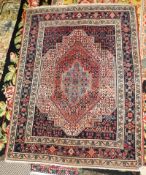 An antique Persian Senneh rug, the central geometric ruby medallion on a midnight blue ground within