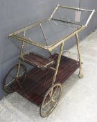 A 1960s designer brass faux bamboo drinks trolley, having glass insert top over veneered