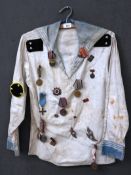 A 1950s sailor's tunic with a large quantity of Communist Russia, and other, period enamel badges