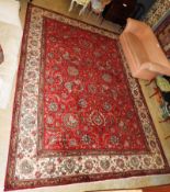 A fine Persian signed Tabriz carpet, the all over palmette and vine design on a ruby ground within a