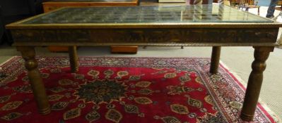 An early 20th Century Indian brass clad dining table, the rectangular bevelled glass insert over