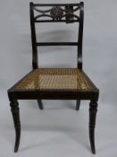 A pair of early 19th Century Regency ebonised and gilt decorated side chairs, the cret decorated