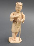A Meiji Period Japanese bone okimono of a fisherman holding a staff, H. 16cm.
