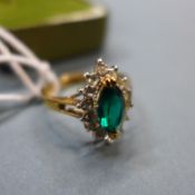 An 18k gold marquise cut emerald and diamond cluster ring