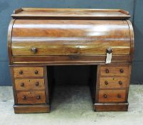 A 19th Century early Victorian mahogany roll top desk, the solid top enclosing fitted interior and