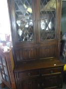 Priory style dark oak wall unit with linen fold panels and leaded glass doors