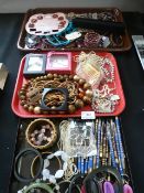 Three trays containing a large quantity of decorative costume jewelry,make-up pencils,etc