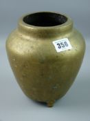 A Chinese brass vase of ovoid form on three feet, the base marked with two swirling dragons around a