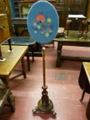 A Victorian mahogany polescreen with embroidered oval face panel, turned column base with carved