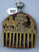 An antique brass horse mane comb decorated with a two team horse and plough and farmer before a