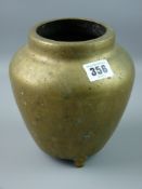 A Chinese brass vase of ovoid form on three feet, the base marked with two swirling dragons around a