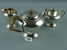A three piece silver tea service comprising teapot of tapered form to a stepped pedestal and with