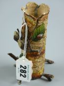 A cold painted metal vase in the form of a hollow tree trunk with protruding leafy twigs and
