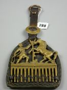 A vintage brass horse mane comb with horse and trainer decoration on leather mount with strap and