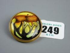 A Moorcroft enamel brooch with stylized tree patterns in a gilt metal frame with clip, marked '