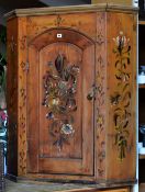 A pine hanging corner cupboard with single arched door and profusely painted in the barge ware style