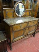 A 1930's oak railback sideboard with central circular mirror, two frieze drawers and two cupboard