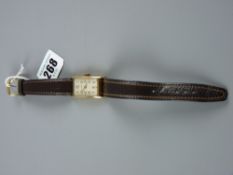 A gent's nine carat gold encased Waltham wristwatch with oblong dial and leather strap, the slightly