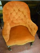 A late Victorian button upholstered armchair on carved front supports and castors, 89 x 67 cms