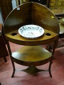 A Sheraton style mahogany corner washstand with top shelf having china recesses and the base shelf