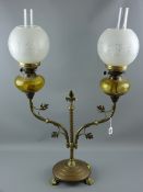 A twin branch brass oil lamp, twist central column on a circular three footed base, leaf adorned